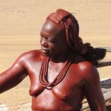 Diese Himba ist gerade dabei ein Dach mit Kuhmist abzudecken.
